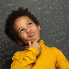 Un niño pensativo con un suéter amarillo, rodeado de fórmulas matemáticas y químicas en una pizarra, como si estuviera en el colegio.