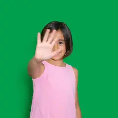 Niña de 4-5 años muestra timidez, cubriendo su rostro con la mano.