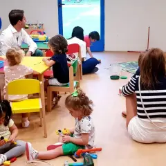 Niños jugando y un adulto observando, parte de lo que es el periodo de adaptación en un aula.