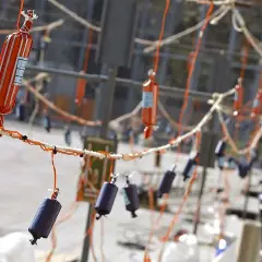 Petardos colgados listos para las **actividades Fallas para niños**. Un hombre al fondo prepara el espectáculo.