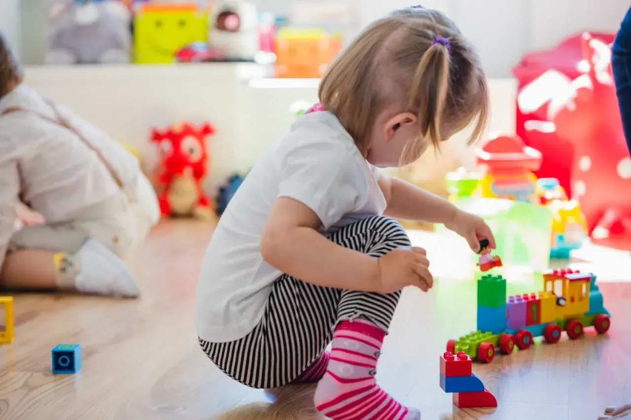 Niña jugando con bloques, concentrada en su mundo, un ejemplo de egocentrismo infantil.