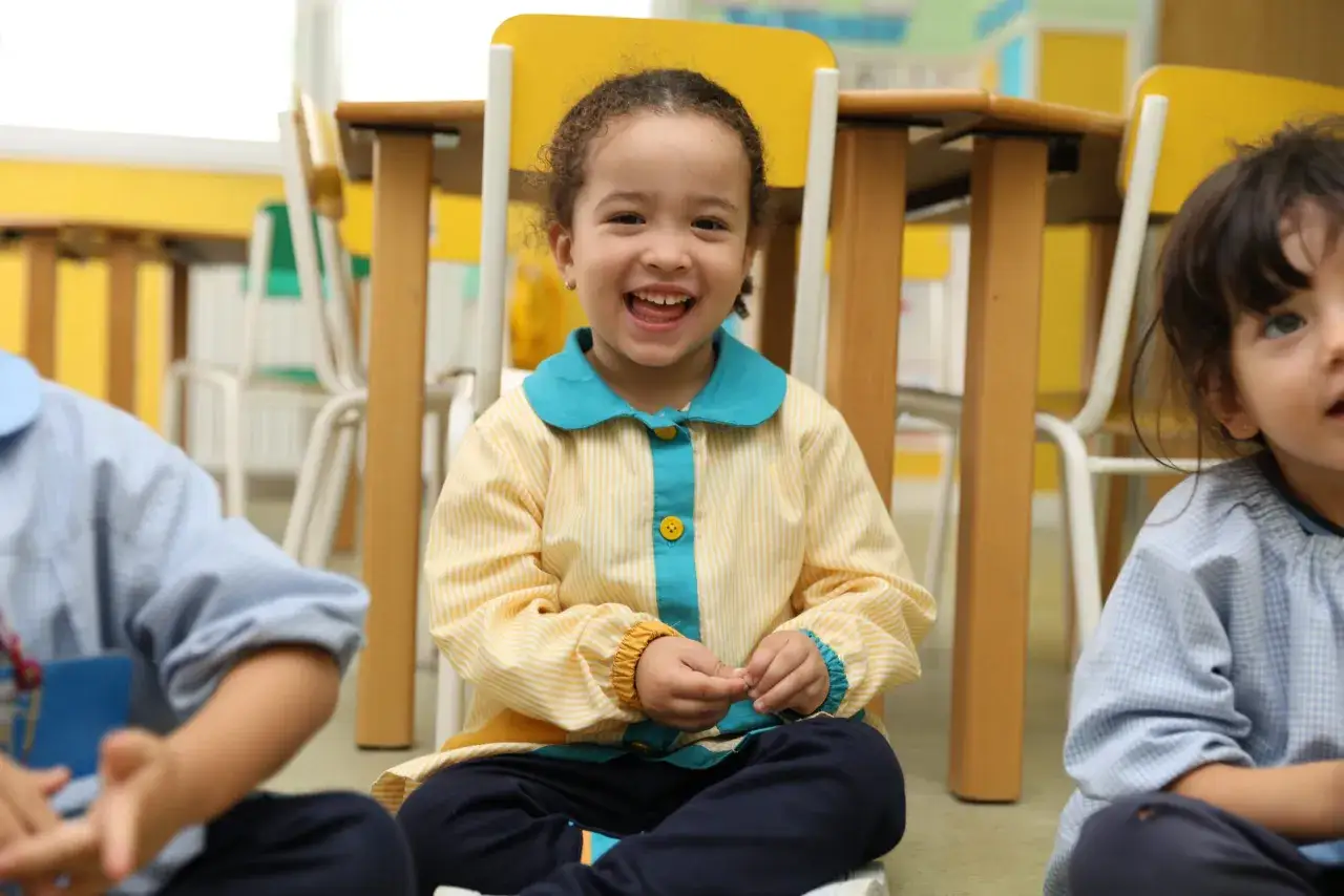 Ni&ntilde;a sonriente en clase, aprendiendo frases positivas para ni&ntilde;os de infantil.