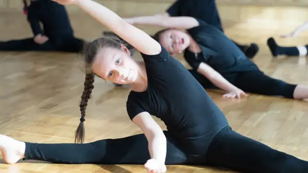 Niñas bailarinas estirando sus piernas en el suelo.